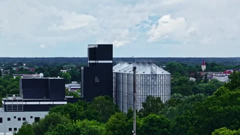 Overcast Flyover of Grain Silos beside Dark Warehouse and Green Trees Stock Footage 341544295