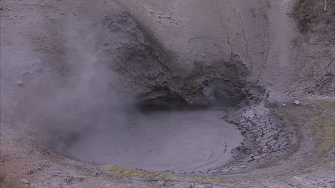 Overcast shot of bubbling mud pit at Yellowstone, with thin cloud of steam. Stock Footage 86755710