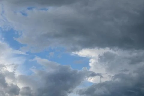 Overcast sky with dense gray clouds and small gaps of blue sky visible betw.. Stock Photos