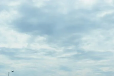 Overcast sky with scattered clouds and a solitary street lamp in the distance 스톡 사진