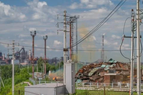 Overcast view shows electrical substation, transformers, poles, rusted metal  Stock Photos