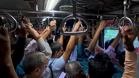 Overcrowded train carriage with commuters holding handles 库存影片 342129421