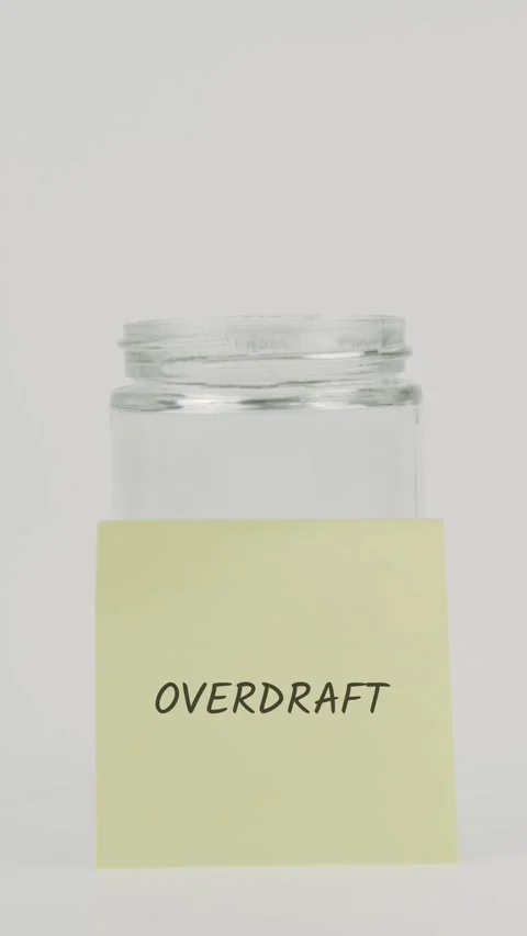 Overdraft text or word on yellow sticky note attached to glass jar with hand Stock Footage 311762161