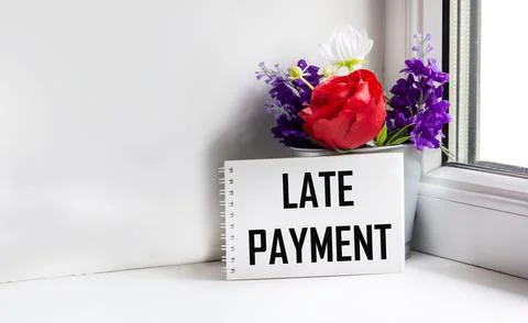 OVERDUE PAYMENT on a light background in an open notebook next to a bouquet o Fotos de archivo