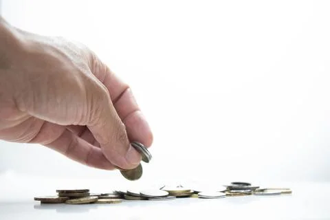 Overexposed image of a young man putting a coin on a group of coin. Selective Stock Photos
