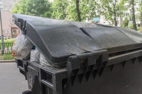 Overfilled garbage bin with plastic bags on city street conceptualizing mun.. Photos