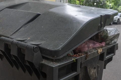Overfilled garbage bin with plastic bags on city street conceptualizing mun.. Stock Photos