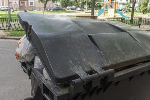 Overfilled garbage bin with plastic bags on city street conceptualizing mun.. Stock Photos