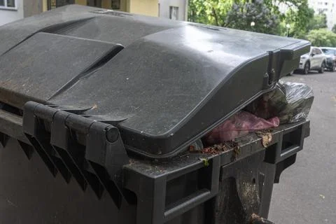 Overfilled garbage bin with plastic bags on city street conceptualizing mun.. Stock Photos