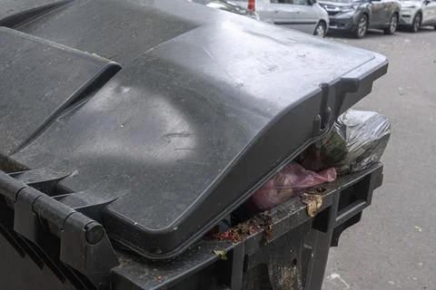 Overfilled garbage bin with plastic bags on city street conceptualizing mun.. Stock Photos