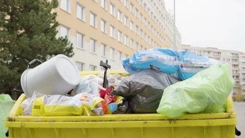 Overfilled yellow garbage can for plastic in an urban area - closeup Stock Footage 164971846