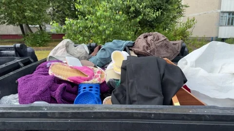 Overflowing black dumpster filled with discarded clothes, slippers Stock Footage 339366755