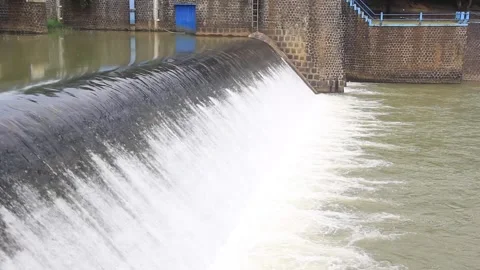 Overflowing dam with smooth cascading water, a rustic stone foundation 库存影片 302334512