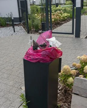 Overflowing garbage bin with plastic cups and trash on street Stockfoto's