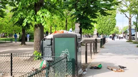 Overflowing Public Garbage Bin in a Sunny Paris Park Stock Footage 335118217