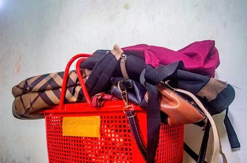 Overflowing red plastic basket filled with various handbags and purses, sho.. Photos