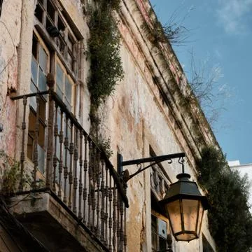 An overgrown and weathered Old Town facade with a streetlamp and balcony Stock Photos
