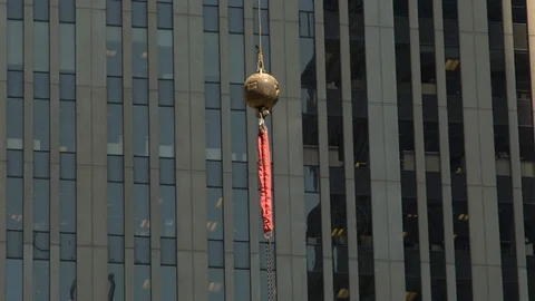 An overhaul ball hook of a construction crane drifts in front of a skyscraper Video stock 96124406