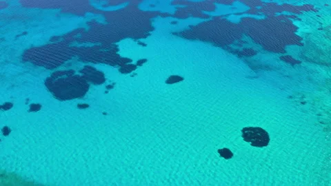 Overhead aerial drone view of the clear turquoise sea patterned with dark Stock Footage 339304035