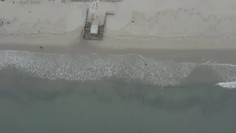 Overhead aerial strafes over the waves crashing on the Santa Barbara shore Видео 150417976