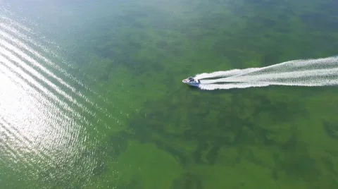 Overhead aerial tracking shot as fun recreational speed boat motors by in lagoon Video stock 63305666