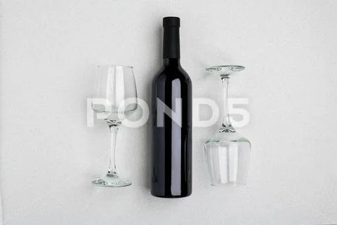 Overhead angled view of a large bottle of red wine, drinking glasses on white Stock Photos