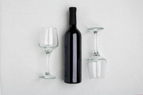 Overhead angled view of a large bottle of red wine, drinking glasses on white Stock Photos
