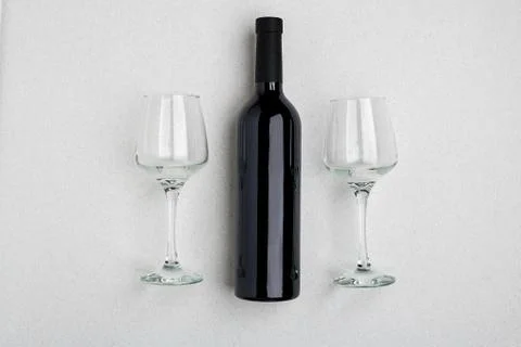 Overhead angled view of a large bottle of red wine, drinking glasses on white Stock Photos