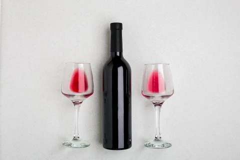 Overhead angled view of a large bottle of red wine, drinking glasses on white Stock Photos