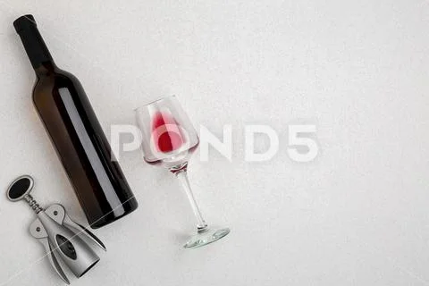 Overhead angled view of a large bottle of red wine, drinking glass on white Stock Photos