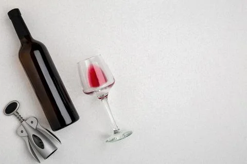Overhead angled view of a large bottle of red wine, drinking glass on white Stock Photos