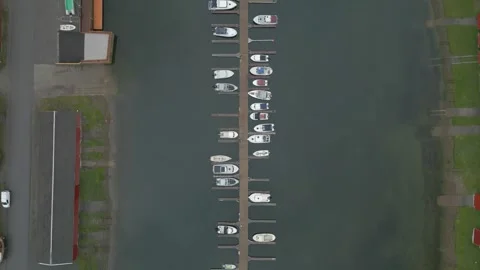Overhead arial shot of a mirror flat water marina with private small boats Stock Footage 247003637