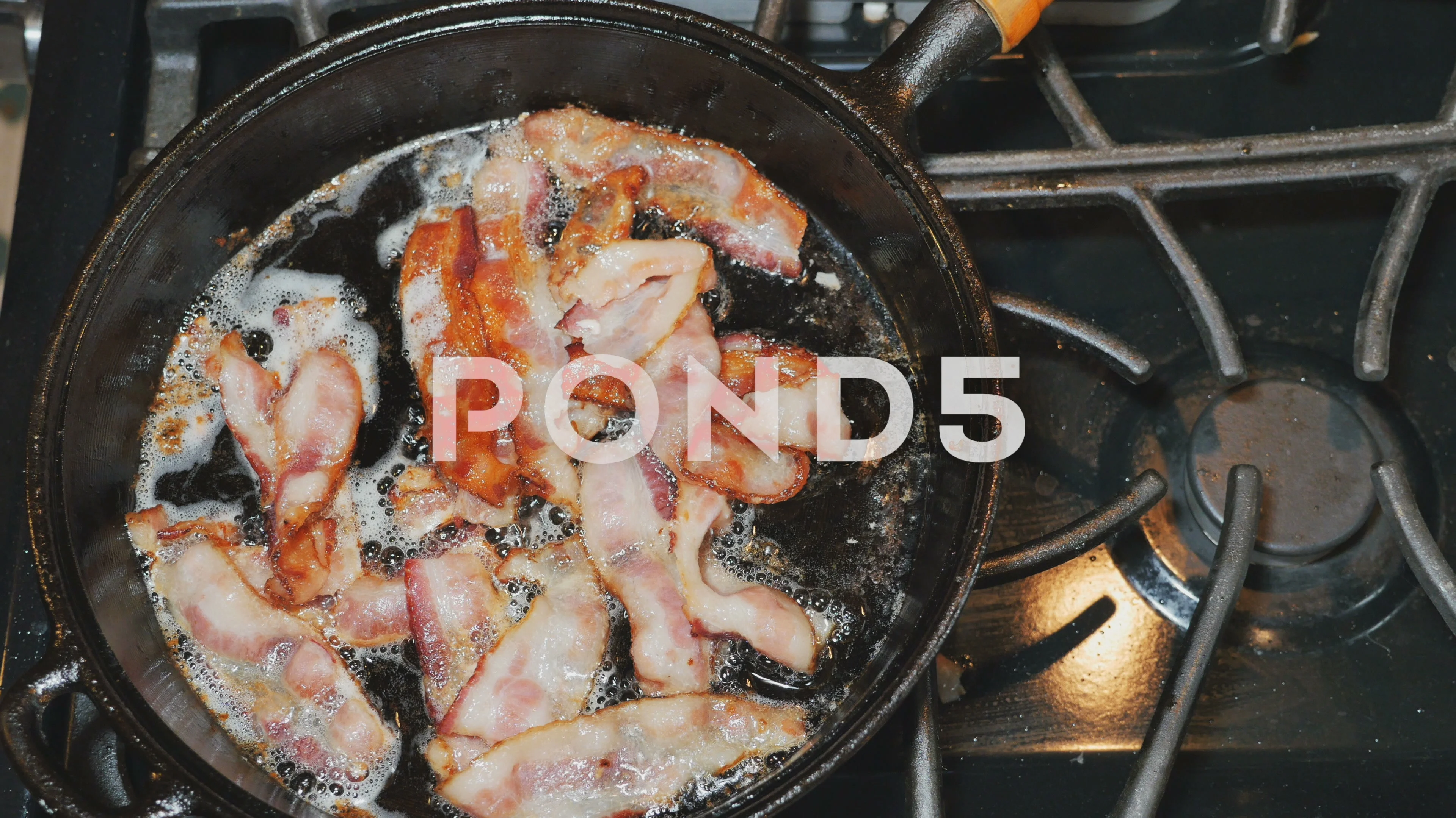 Bacon frying in stove top pan. Sizzling bacon strips in silver skillet.  Stock Photo