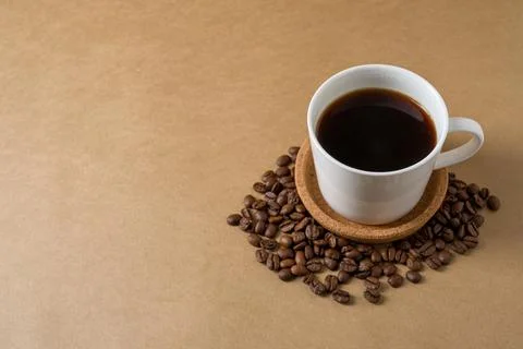 Overhead black coffee cup surrounded by roasted beans with spacious neutral.. Stock Photos