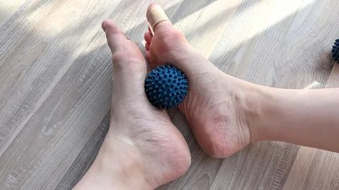 Overhead Close Up of Bare Feet Rolling Spiky Massage Ball Wearing Toe Space.. Stock Photos