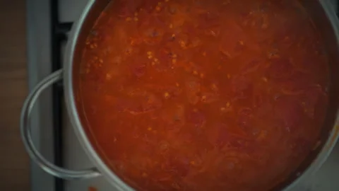 Overhead close-up of boiling tomato sauce in a metal pot. Active bubbles and Stock Footage 345579937