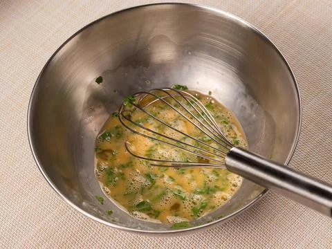 Overhead Close-Up of Egg Mixture Being Whisked with Parsley Foto stock