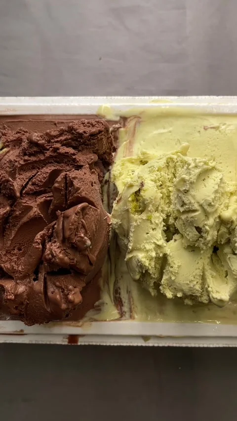 Overhead close view of scooped chocolate and pistachio ice cream melting softly Stock Footage 341661129