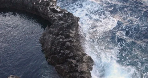 Overhead of contrast between stormy waves on cliffs near calm natural waterhole Stock Footage 104791104