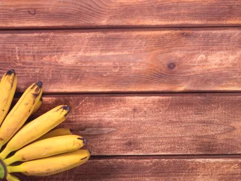 Overhead copy space with bunch of mini bananason a wooden table Stock Photos