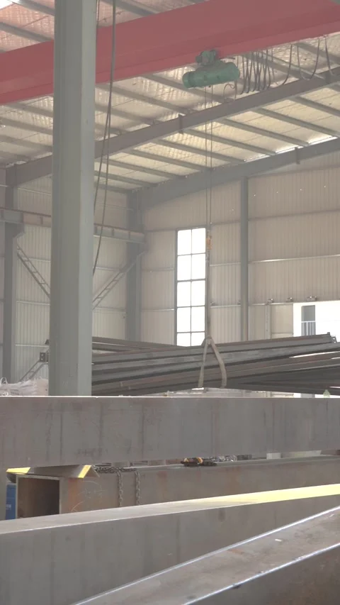 Overhead Crane Lowering Structural Steel Beams in Industrial Fabrication Stock Footage 339384640