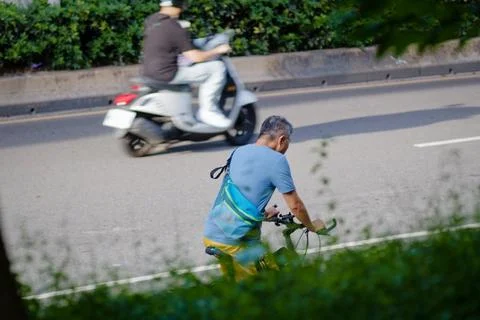 Overhead Cyclist Riding Between Traffic Lanes With Scooter Passing in Taipei 写真素材