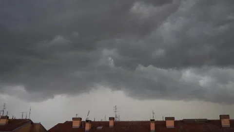 Overhead dark storm clouds loom ominously, casting shadows over rooftops in a Stock Footage 317576517
