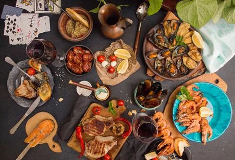 Overhead of dinner table. Assorted delicious grilled barbecue meat and seafoo Stock Photos