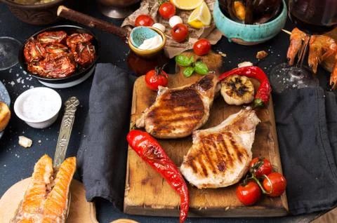 Overhead of dinner table. Assorted delicious grilled barbecue meat and seafoo Stock Photos