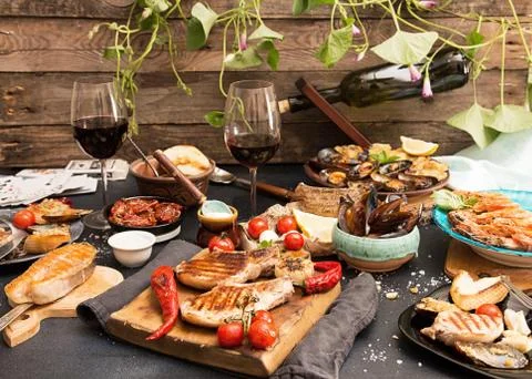 Overhead of dinner table. Assorted delicious grilled barbecue meat and seafoo Stock Photos