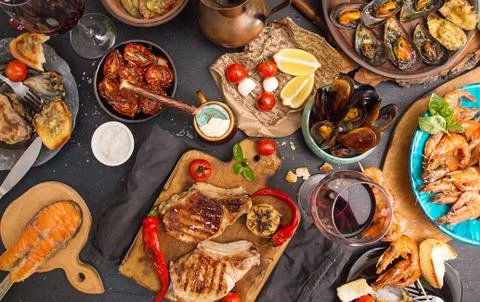 Overhead of dinner table. Assorted delicious grilled barbecue meat and seafoo Stock Photos