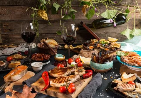 Overhead of dinner table. Assorted delicious grilled barbecue meat and seafoo Stock Photos