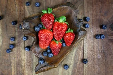 Overhead Display of Fresh Strawberries and Blueberries in a Rustic Wood Bowl Stock Photos