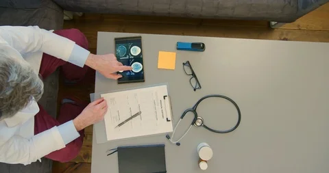Overhead Of Doctor Analyzing Brain CT Scan While Filling Medical Form 4K Stock Footage 92478265